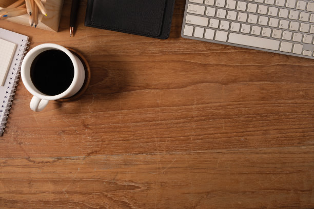 简单的工作场所俯视图，木桌上有一杯咖啡，铅笔和记事本。带复制空间的俯视图。图片下载