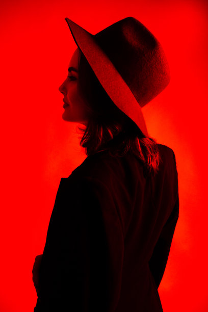 一个戴着帽子的女孩在红光下的剪影图片下载