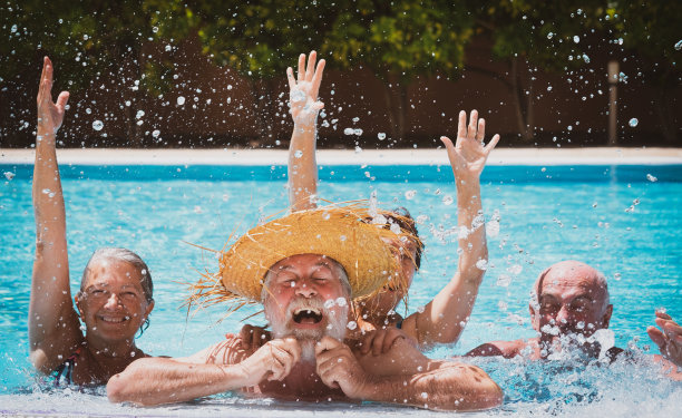 快乐的一群成熟的朋友一起享受户外游泳池在阳光下玩耍。假期和夏季概念图片下载