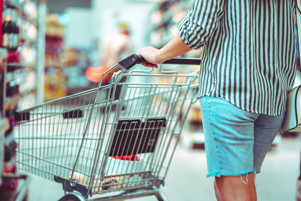 超市里推着购物车的购物者。在杂货店买食物图片下载