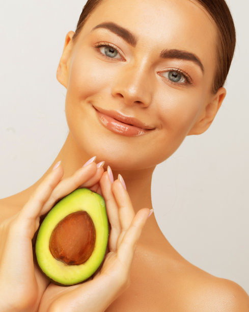 美丽的年轻女子与新鲜的牛油果在浅色背景。高质量照片图片下载