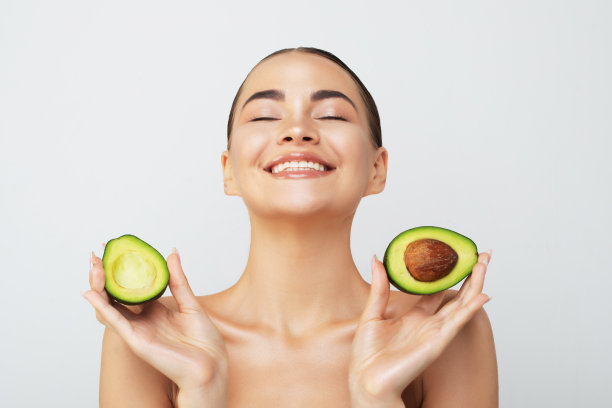 美丽的年轻女子与新鲜的牛油果在浅色背景。高质量照片图片下载