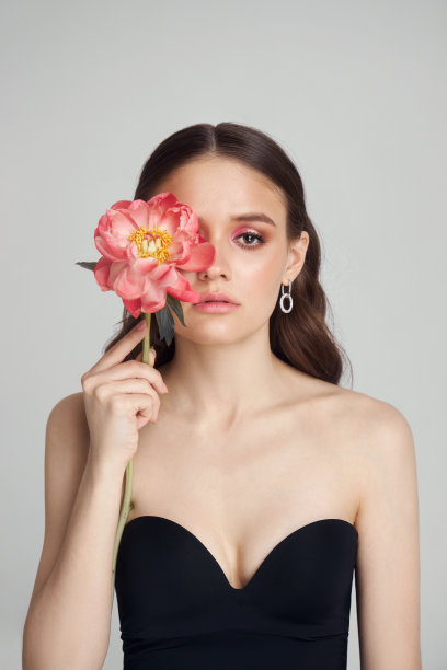 带着粉色大花的可爱女人，画室肖像。完美的身材，女人脸上的粉色妆容图片下载