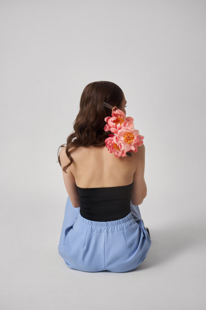 带着粉色大花的可爱女人，画室肖像。完美的身材，女人脸上的粉色妆容图片下载