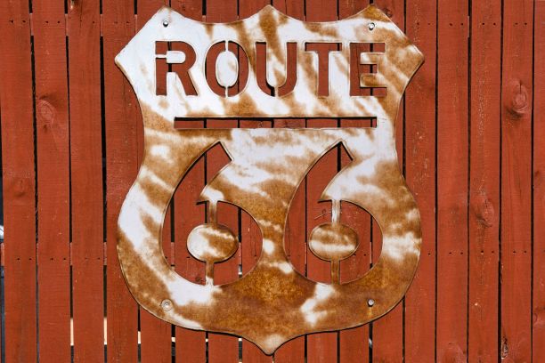 锈迹斑斑的老旧木栅栏上有一个老式的66号公路路标图片下载