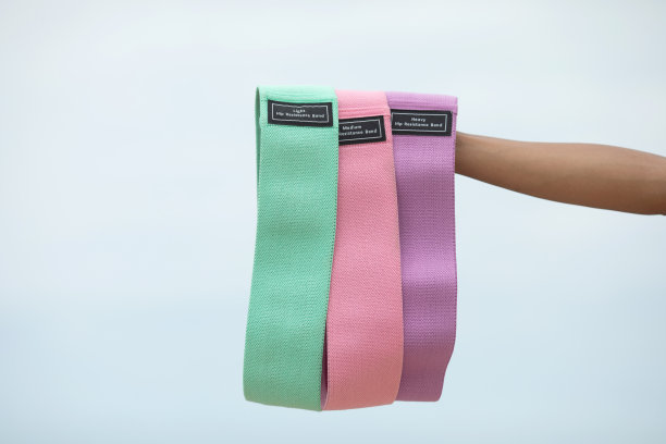 剪短的年轻苗条女子手持健身弹性阻力带的照片。图片下载