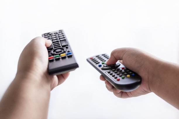 男孩的手拿着两个电视遥控器，孤立在白色背景下图片下载