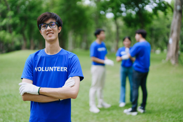 多民族志愿者拿着黑色垃圾袋收集塑料垃圾，以减少公园的污染。图片下载