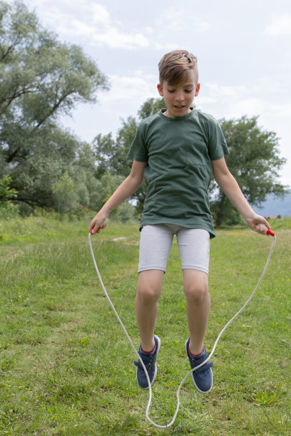在一个美丽的春日，一个男孩在公园里跳绳玩得很开心。图片下载
