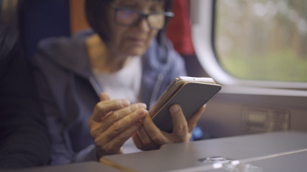 一位坐在火车车厢里使用智能手机的老妇人的手特写图片下载