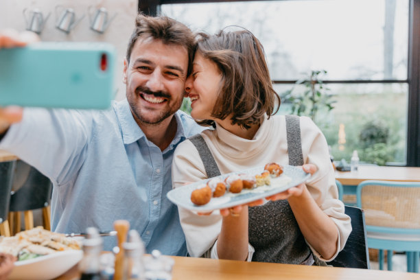 拍摄个人使用智能手机在社交媒体平台上分享用餐体验的照片，强调技术在食物分享中的作用。图片下载