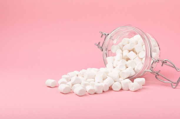 粉红色背景上的松散棉花糖。白色的棉花糖平铺。甜食和零食当零食。咀嚼糖果的特写。副本的空间。放文字的地方。冬季食物概念。图片下载