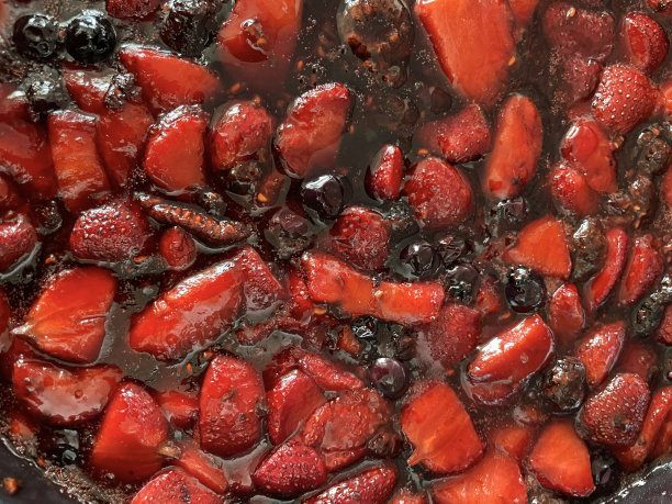 全画幅的不粘锅图片，里面有夏天的水果，糖浆和天然果汁，炖和煨，草莓，黑加仑子和覆盆子，高架视图图片下载