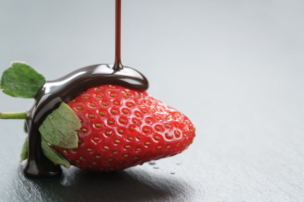 在石板背景上，将巧克力酱浇在新鲜成熟的草莓上图片下载