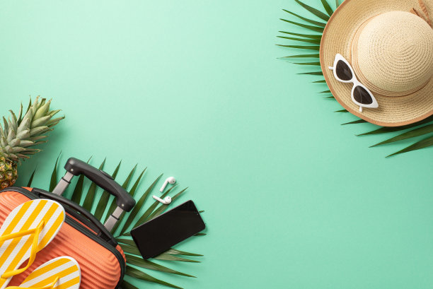 暑期旅行概念。上面的照片是一个橙色的行李箱，上面有拖鞋，草帽和太阳镜，棕榈叶在孤立的绿松石背景上，带有copyspace图片下载