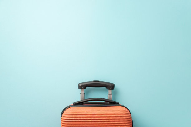 想要一个夏日度假吗?淡蓝色背景上的橙色行李箱的俯视图，为文字或广告做好了准备图片下载
