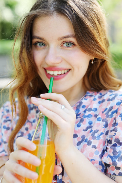 特写肖像，迷人的年轻女子穿着裙子，手里拿着冰凉的苏打水，炎热的晴天，假期和假期。图片下载