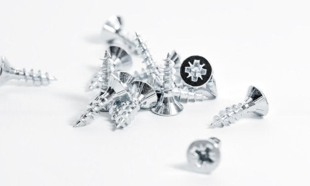 螺丝散落在桌子上。一堆镀锌螺丝。图片下载