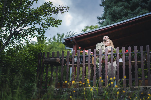 一对幸福的中年白人夫妇站在乡间别墅的露台上拥抱。夏日生活写真图片下载