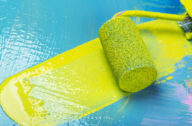 在蓝色背景上涂上黄色油漆的滚筒图片下载