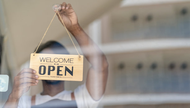 一位服务员站在咖啡馆门口，拿着食物。成功的启动和新的店铺概念图片下载