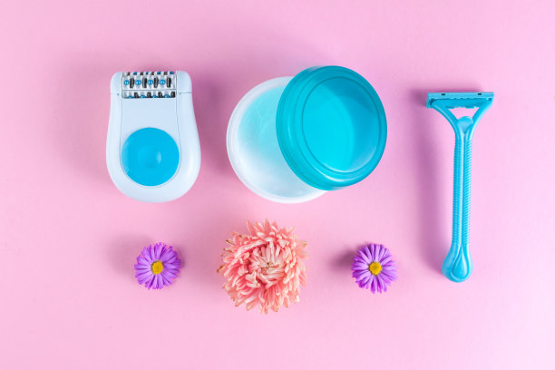 脱毛膏、面霜、女性剃须刀和粉红色背景上的花朵。脱毛。去除多余的毛发。水疗和女性护理。拔毛的概念图片下载
