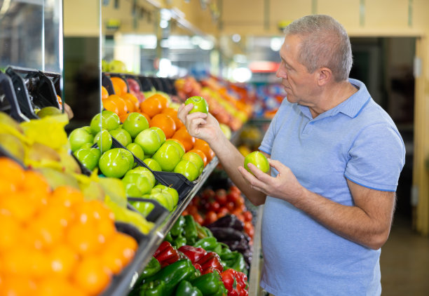 集中的成熟男性买家养老金领取者选择有机奶奶史密斯青苹果在大卖场图片下载