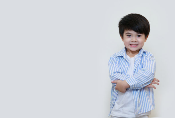 一个亚裔美国男孩的肖像，穿着朴素，双臂交叉，背景是白色的。图片下载
