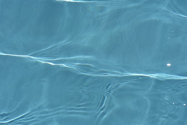 蓝蓝的水面上泛起涟漪。散焦模糊透明蓝色透明平静水面纹理与飞溅和气泡。水波与闪亮的图案纹理背景。图片下载