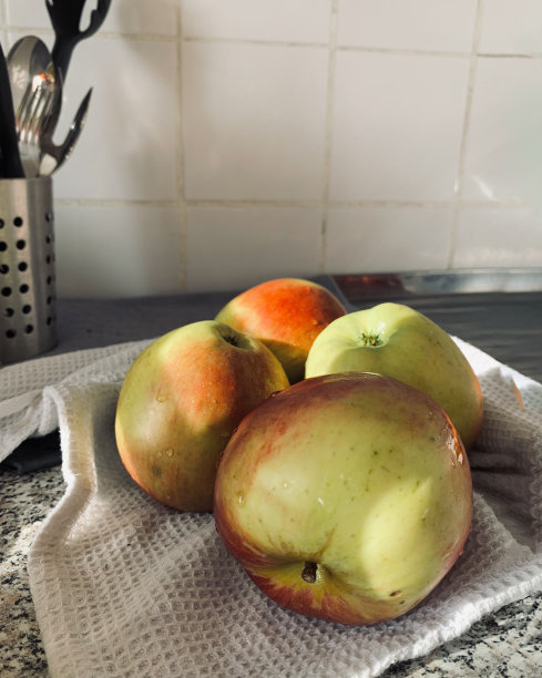 厨房里白色的桌子上放着秋天的苹果，白色的墙壁上投射着夕阳的影子图片下载