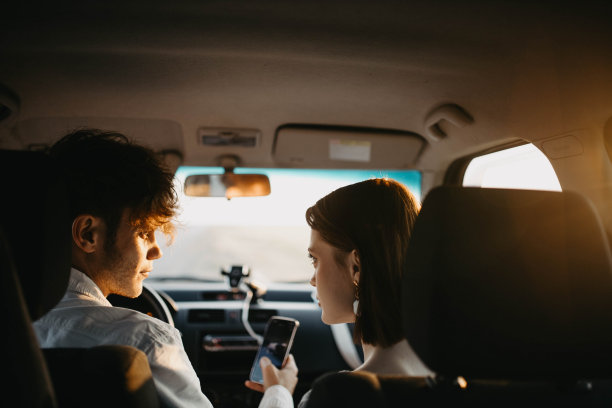 相爱的情侣在车里看着智能手机选择一条旅行路线，使用应用程序图片下载