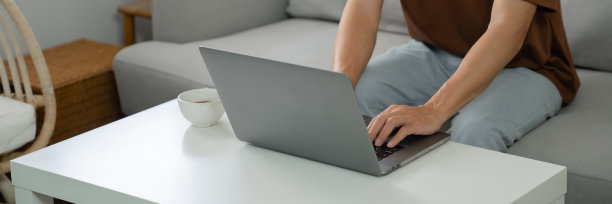 在家里工作年轻的亚洲人在笔记本电脑上工作，而坐在家里早上的生活方式图片下载