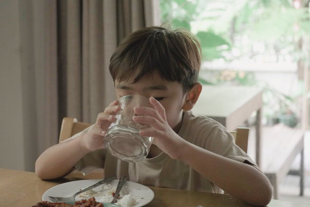 小男孩用桌子上的杯子喝水图片下载