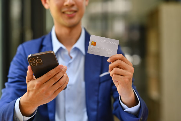 男子持有信用卡，使用智能手机在线购物或在线支付。图片下载