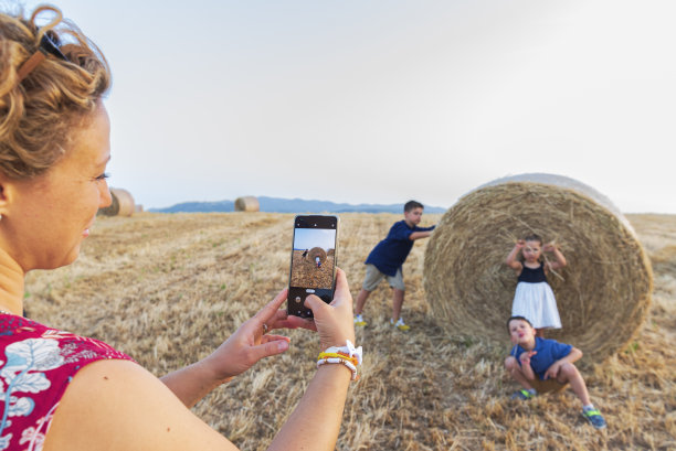 农民父母在农村农场拍摄拿着干草捆的孩子图片下载