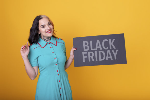 一个漂亮的女人拿着黄色背景的黑色星期五标志图片下载