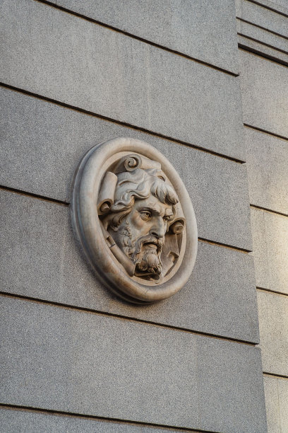 一座古老的雕塑坐落在一座建筑物的一侧图片下载