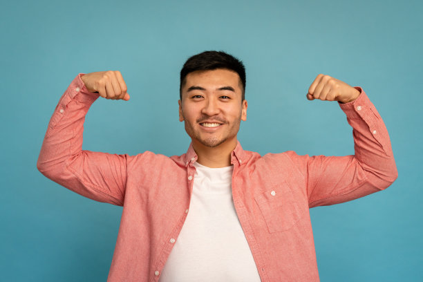 微笑的男人在演播室里弯曲双臂。图片下载