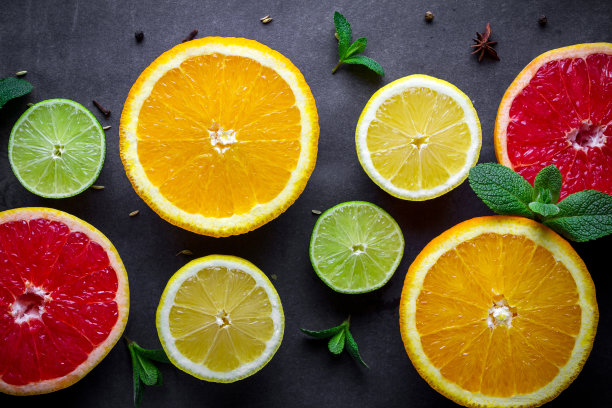 新鲜、成熟的柑橘类水果和绿色薄荷叶在深色背景下。健康食品和饮食。维生素图片下载