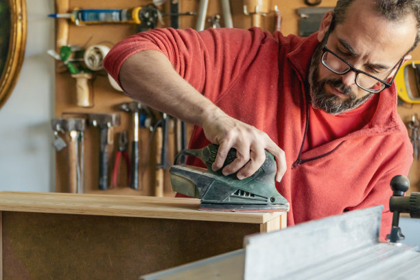 戴眼镜的木匠在他的车间里使用电动打磨机图片下载