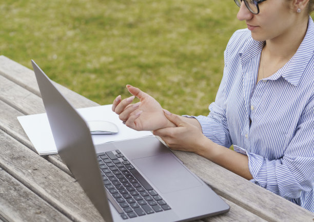 一位女商人因为使用笔记本电脑而痛苦地握着手腕图片下载