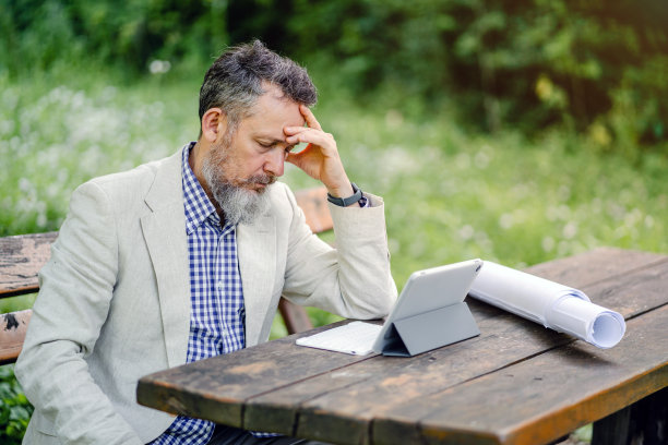 压力大的资深企业家在大自然中工作时头痛图片下载