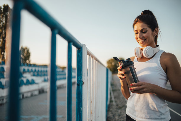 一位运动女性在户外训练和喝水后休息的画像图片下载
