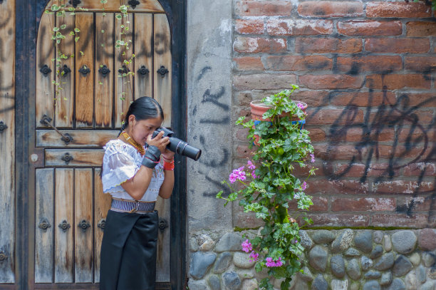 漂亮的土著女孩学习街头摄影，给开花的植物拍照图片下载