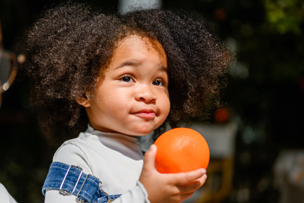 小女孩拿着橘子和家人玩耍的照片图片下载