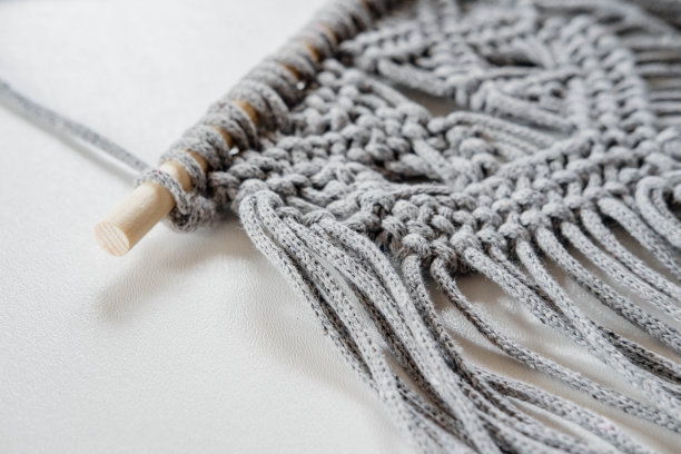 白色背景上手工制作的灰色流苏纹理图案特写。环保的现代概念DIY编织自然装饰在室内。女人的爱好。图片下载