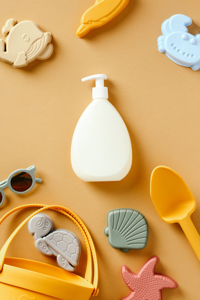防晒乳液与沙子玩具的彩色背景。图片下载