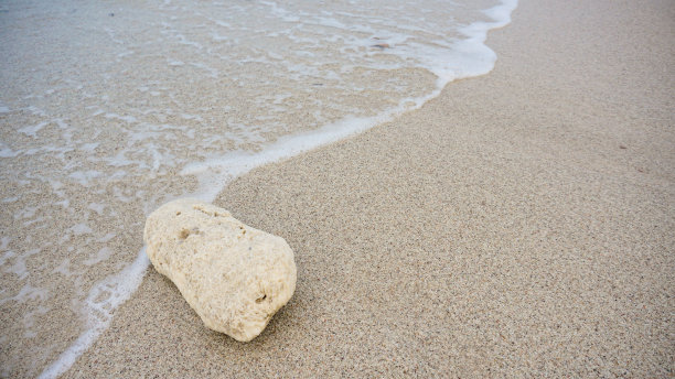 沙滩上的珊瑚或岩石被带泡沫的蓝色海水拍打着。欣赏美丽的热带海滩，岩石，珊瑚，海浪，沙滩和南榜卡连达的滨海海滩图片下载