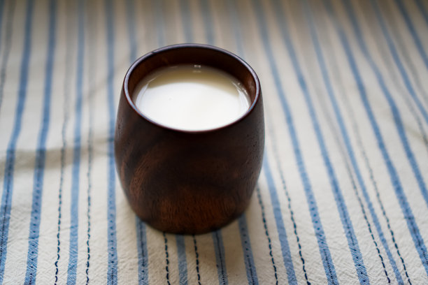 图为早餐桌上装着豆浆的漂亮的实木马克杯。图片下载