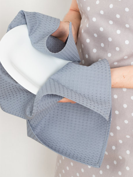 一位年轻女子用厨房毛巾擦拭白色瓷盘图片下载